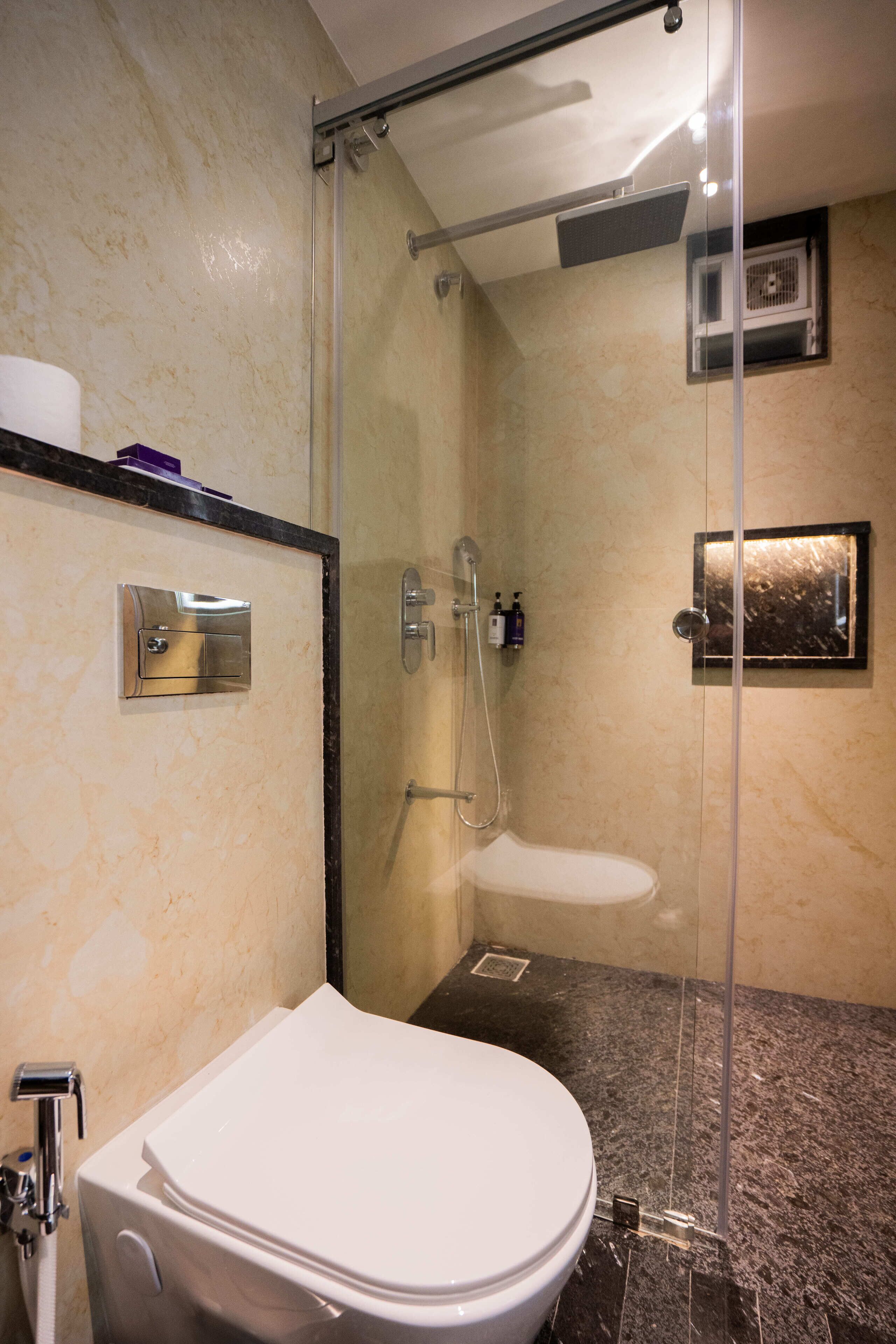 Ein modernes Badezimmer mit einer Duschkabine aus Glas, einer weißen Toilette und einem marmorbodenbelagten Boden.