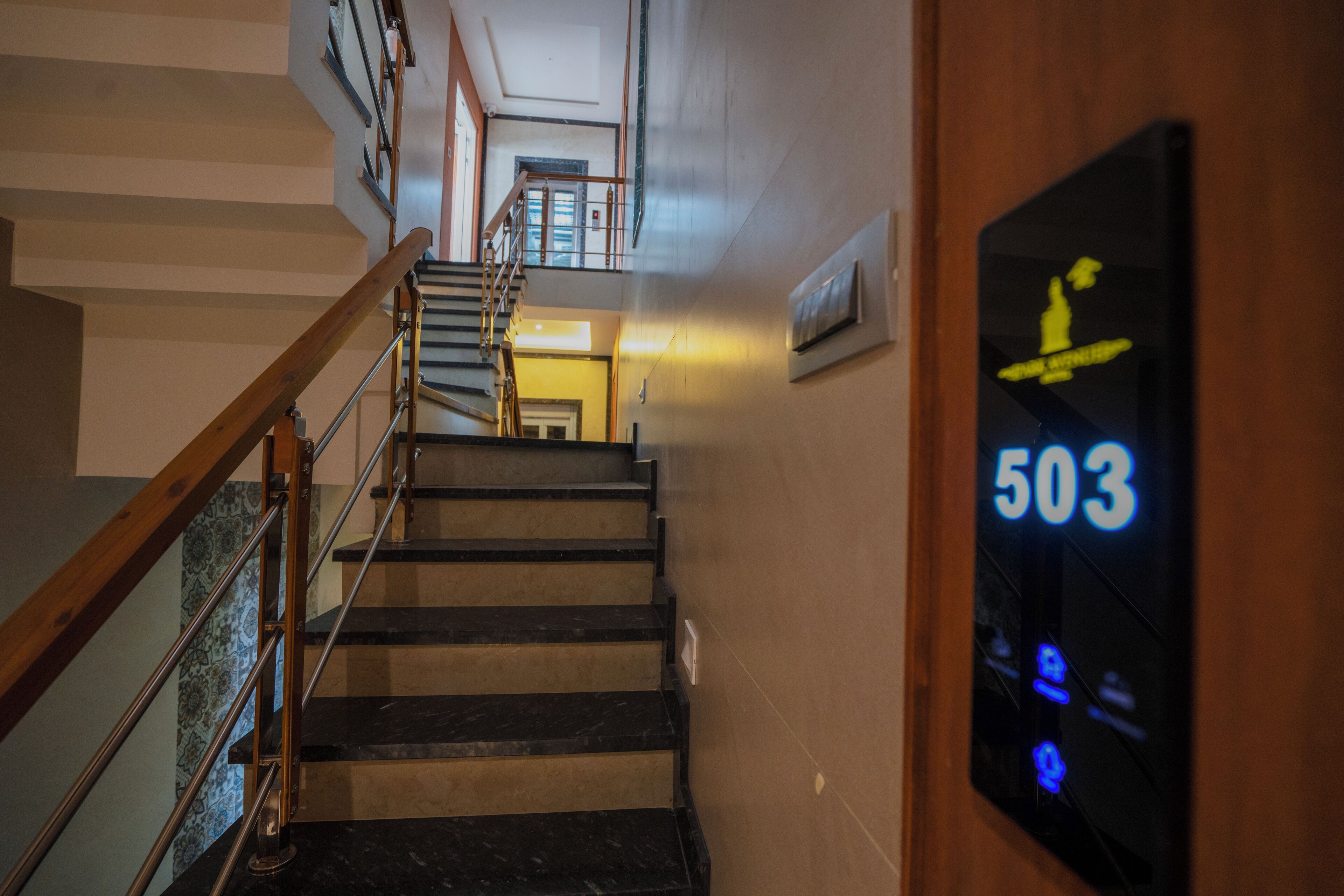 A staircase with a wooden handrail and black steps, leading to an upper floor. A digital sign displays the number 503.