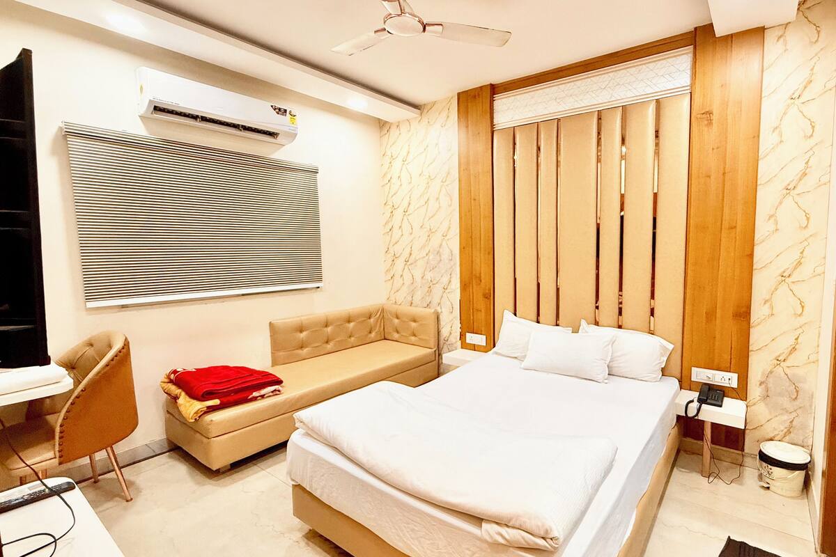 Une chambre moderne équipée d’un lit, d’un canapé, d’un bureau et d’un appareil de climatisation.