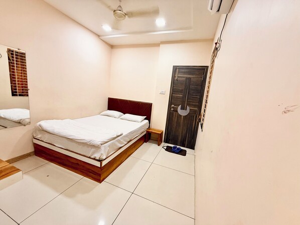 Un dormitorio con una cama, cabecera de madera, una puerta y un pequeño banco.
