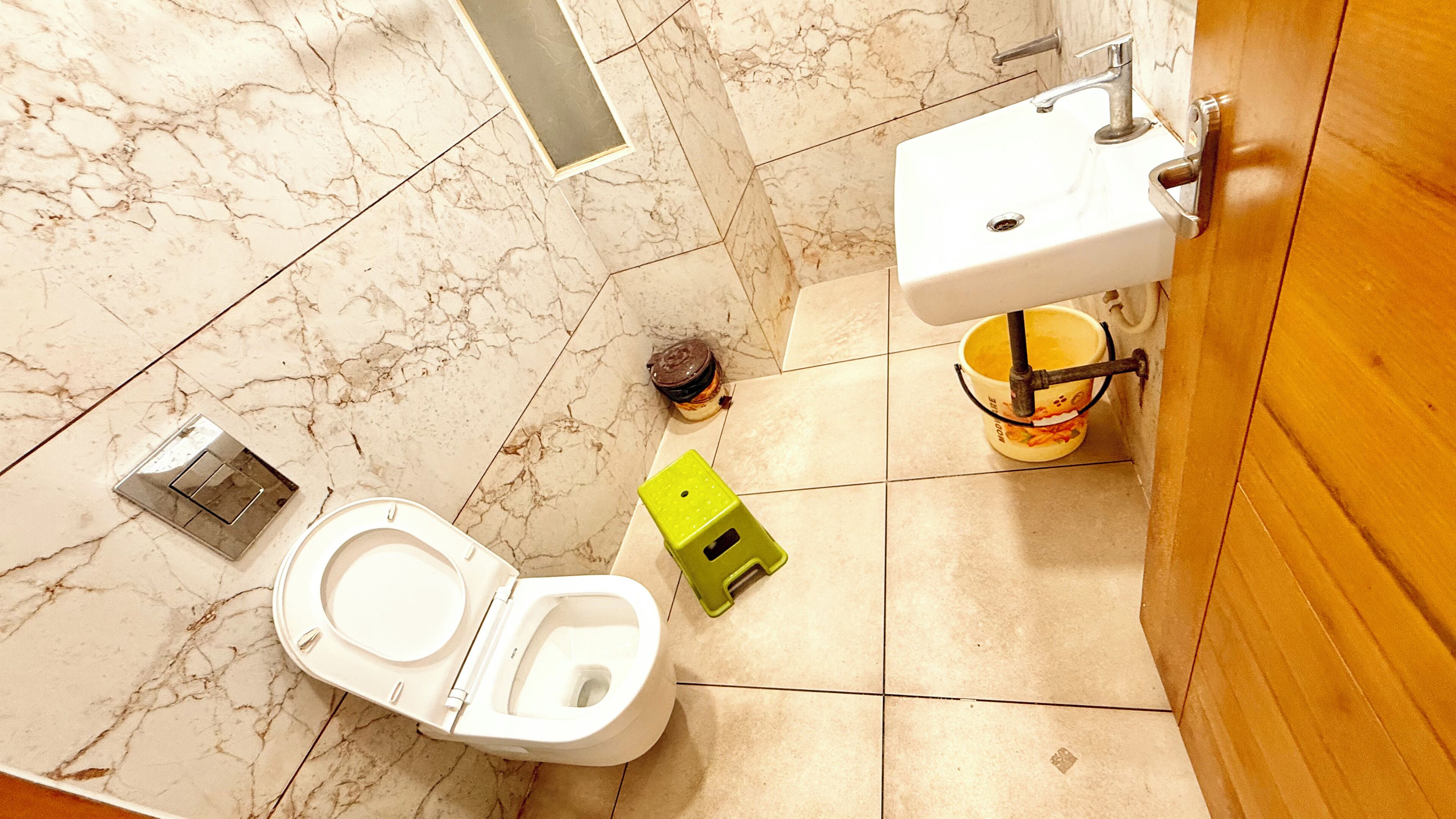 A bathroom with a toilet, sink, and a trash bin.