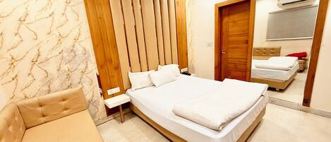 Camera d'albergo con un letto grande, una testiera in legno, un comodino e uno specchio che riflette un secondo letto e un condizionatore d'aria.