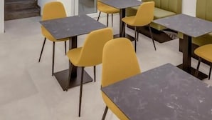 A modern dining area with tables and chairs, a staircase, and a door. - Alba in Cento (Lampedusa)