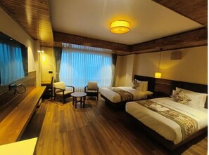 Une chambre d’hôtel avec deux lits, un bureau, une chaise et une petite table.