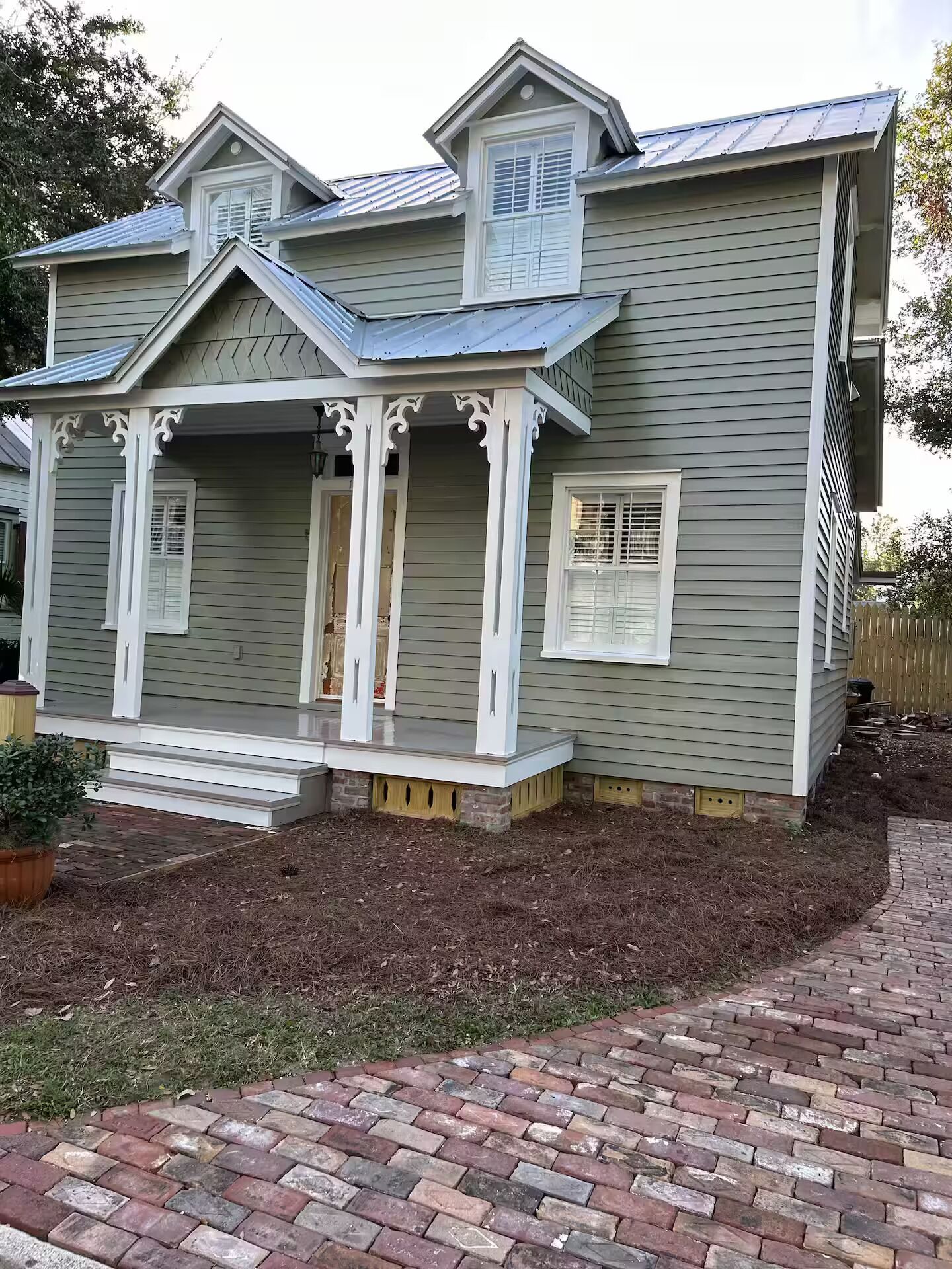 Une maison à deux étages avec un porche, un hall d’entrée couvert et un chemin en briques menant à la porte d’entrée.