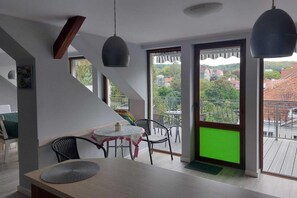 Un espace repas moderne comprenant une table, des chaises et donnant sur un balcon agrémenté d’un tapis vert.