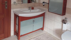 A bathroom with a white sink, red cabinet, and a mirror above it.