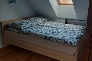 Een kleine kamer met een enkel bed, schuine wand en dakraam.
