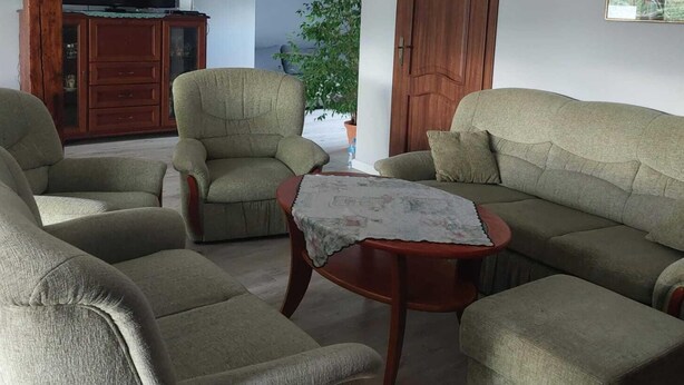 A living room with a sofa, two armchairs, and a small coffee table.