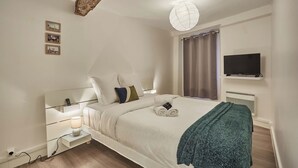 A modern bedroom with a bed, bedside tables, a lamp, a TV, and a globe light. - Superb Apartment in the Center of Paris by Stusioprestige (Paris)