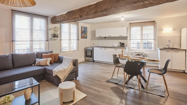 A modern living room with a sofa, ottoman, and dining area with chairs and a table. - Superb Apartment in the Center of Paris by Stusioprestige (Paris)