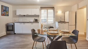 A modern kitchen with white cabinets, a built-in oven, and a dining area with a glass table and black chairs. - Superb Apartment in the Center of Paris by Stusioprestige (Paris)