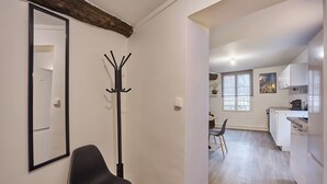 A modern kitchen with white cabinets and a dining area with a black chair and a wooden floor. - Superb Apartment in the Center of Paris by Stusioprestige (Paris)
