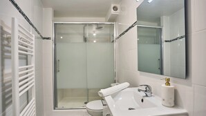 A modern bathroom with a glass shower enclosure, a white sink with a gold faucet, and a toilet. - Superb Apartment in the Center of Paris by Stusioprestige (Paris)