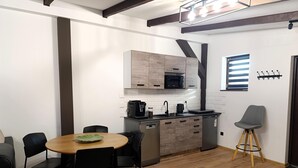 A compact kitchen with modern appliances, a dining area with a round table and chairs, and a small stool. - Holiday Home in Stepnica Near Szczecin Lagoon (Stepnica)