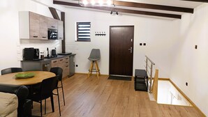 A modern kitchen with a dining area, wooden flooring, and a staircase leading to an upper level. - Holiday Home in Stepnica Near Szczecin Lagoon (Stepnica)