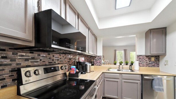 A modern kitchen with an LG stove, a brick backsplash, and a skylight.