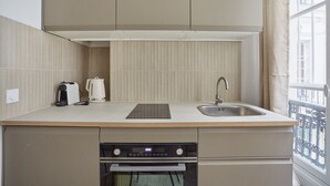 A compact kitchen with a built-in oven, a sink, and a window with a view. - Charming Studio - Le Marais - Bastille (Paris)