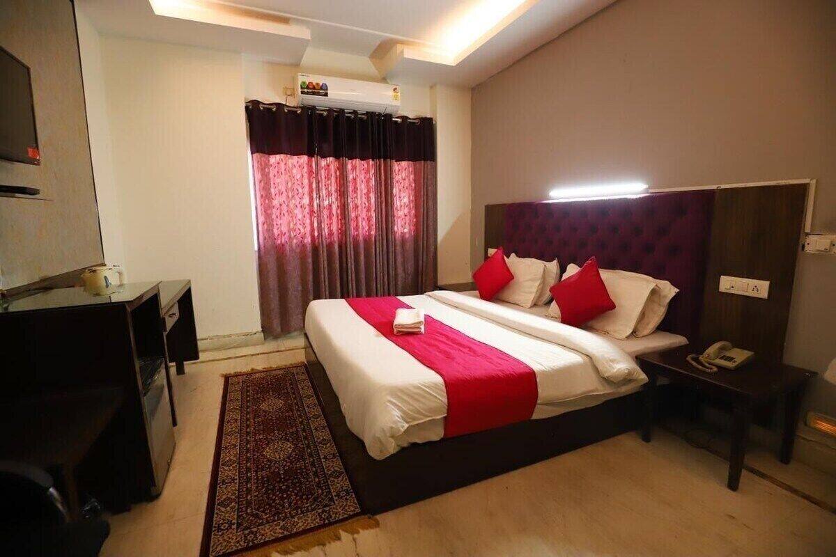 Une chambre d’hôtel avec un lit, un bureau, un téléphone et une fenêtre avec des rideaux.