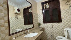 Een badkamer met een wastafel met granieten blad, een grote spiegel, een toilet en een douche.