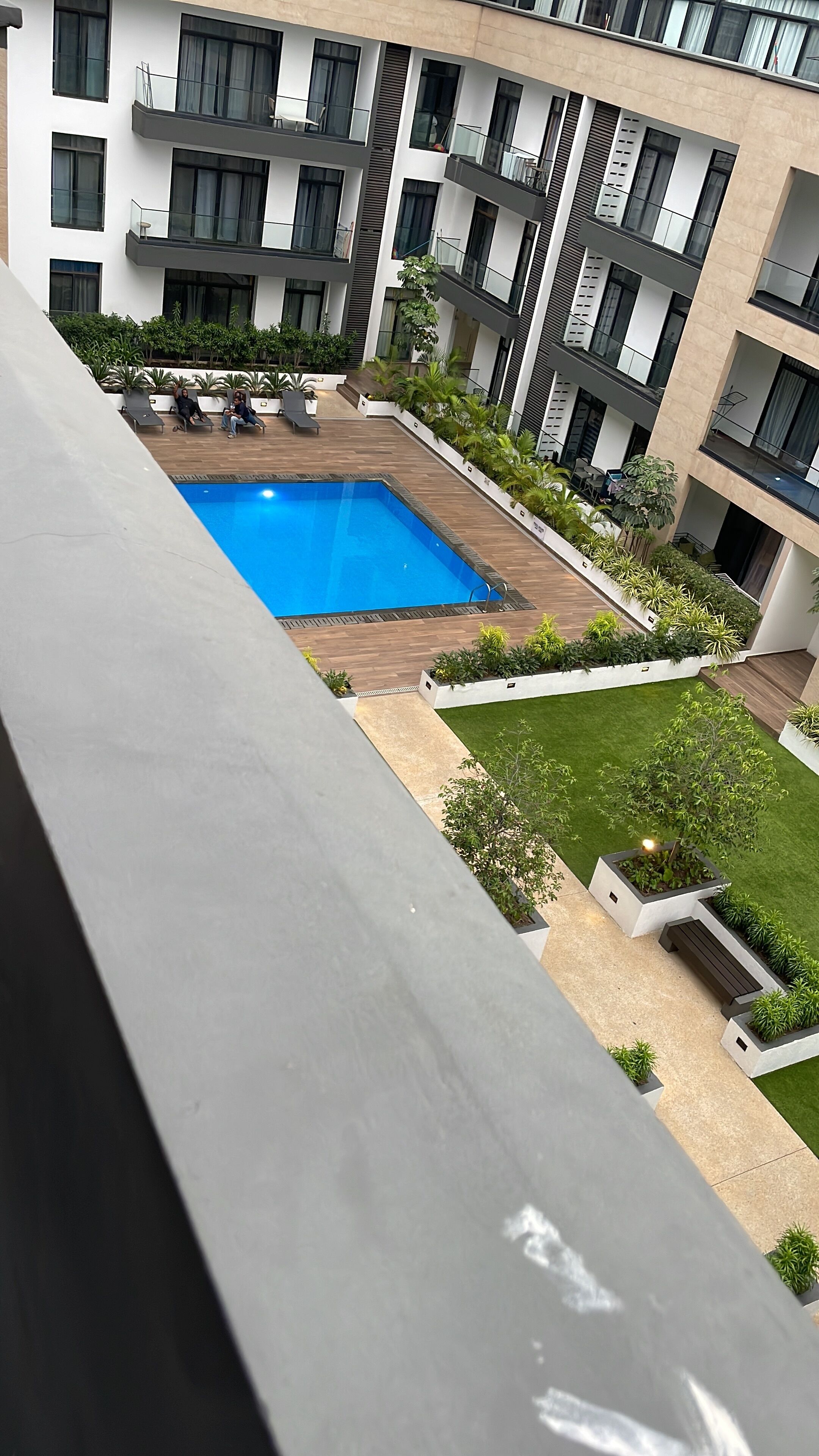 A modern apartment building with a rooftop pool, balconies, and a well-maintained garden.