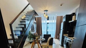 A modern kitchen with a built-in washing machine, a dining area with a table and chairs, and a staircase leading to another level. - Embassy Gardens Studio Suite (Accra)