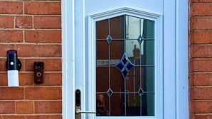 Eine hellblaue Tür mit einem dekorativen Glasfenster und einem kleinen Fenster.