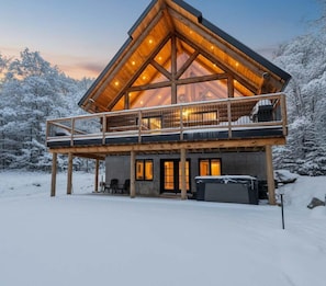 A log cabin with a balcony, wooden deck, and a covered outdoor seating area. - Spa, Game Room, Absolute Comfort | Le Commandant (Saint-Philémon)