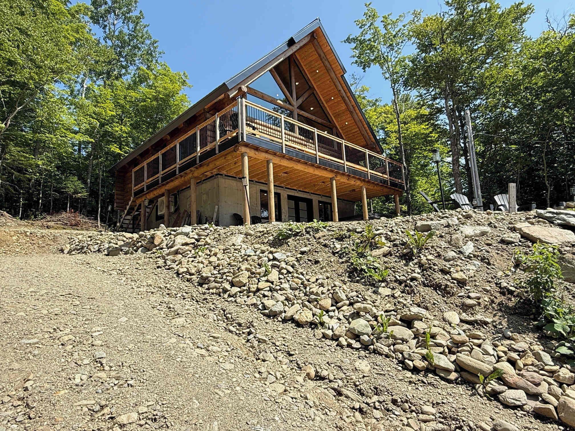 Une cabane dotée d’un toit à forte pente, d’une façade en bois et d’un balcon avec des rampes en métal.