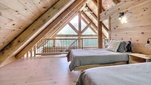 A cozy attic bedroom with a sloped ceiling, two beds, a small table, and a balcony with a railing. - Spa, Game Room, Absolute Comfort | Le Commandant (Saint-Philémon)