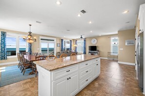 A spacious kitchen with a large island, white cabinetry, and a dining area with a table and chairs. - Beachfront Gulf Retreat w/ Private Boardwalk + Screened Deck | Sleeps 14 | Pet Friendly (Cape San Blas)
