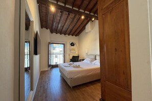 A bedroom with a wooden ceiling, a bed with white linens, and a nightstand with a lamp.