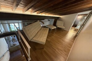 A loft-style room with a wooden ceiling, a sofa, a bench, and a small table.