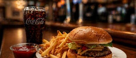 A burger with fries and a Coca-Cola drink on a plate.