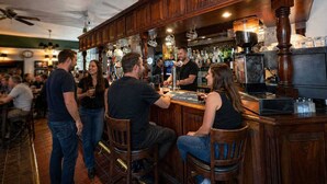A bar area with wooden bar counters, stools, and a bartender serving drinks. - Tree Hotel (Oxford)