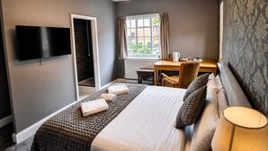 A hotel room with a bed, a desk, a chair, a television, and a window with curtains. - Tree Hotel (Oxford)