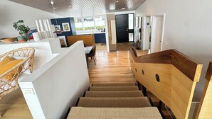 A modern interior with a wooden ceiling, a kitchen area, and a dining space with a staircase. - Modern and family friendly house in Fossvogur in Reykjavik (Reykjavík)