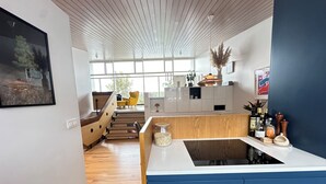 A modern kitchen with a central island, wooden flooring, and a view to the living area. - Modern and family friendly house in Fossvogur in Reykjavik (Reykjavík)