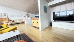 A modern living room with a wooden ceiling, a large TV, and a sofa. - Modern and family friendly house in Fossvogur in Reykjavik (Reykjavík)