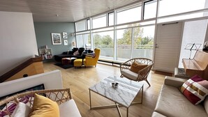 A spacious living room with a large window, a sofa, a coffee table, and a wicker chair. - Modern and family friendly house in Fossvogur in Reykjavik (Reykjavík)