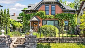 A two-story house with a gabled roof, a front porch, and a stone staircase leading to the front door. - US Bank | Downtown Mpls | Convention Center (Minneapolis)