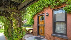 A brick building with a wooden door and window, surrounded by greenery and a patio area. - US Bank | Downtown Mpls | Convention Center (Minneapolis)