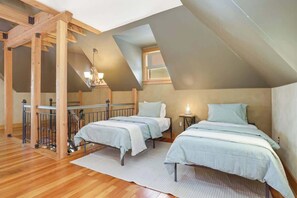 A bedroom with two beds, wooden beams, a small table, and a window. - US Bank | Downtown Mpls | Convention Center (Minneapolis)