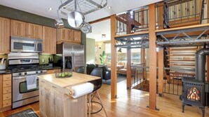 A modern kitchen with stainless steel appliances, a wooden island, and a black wood-burning stove. - US Bank | Downtown Mpls | Convention Center (Minneapolis)