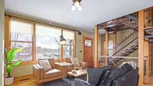A spacious living area with a large window, a staircase, and a sofa. - US Bank | Downtown Mpls | Convention Center (Minneapolis)