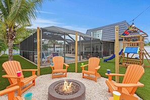 An outdoor seating area with Adirondack chairs, a fire pit, and a play structure. - Heated Pool, Hot Tub, Pickleball · 10 Min to Beach (Bradenton)