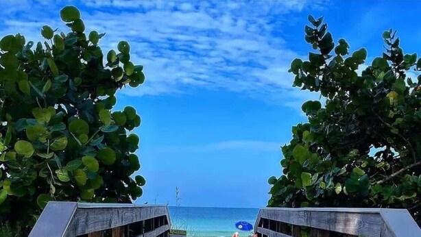 Una passerella di legno che conduce a una spiaggia sotto un cielo sereno.