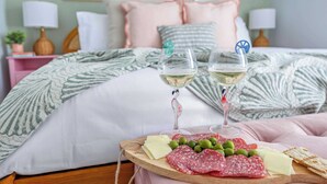 A bedroom with a bed, pillows, a bedside table with a lamp, and a tray with food and drinks.