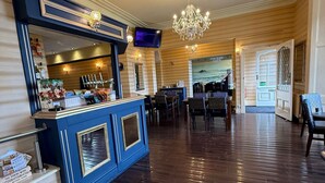 A spacious lobby with a bar area, wooden flooring, and a chandelier. - Baytree Hotel  (Llandudno)