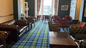A cozy lounge area with a plaid carpet, leather sofas, and a chandelier. - Baytree Hotel  (Llandudno)